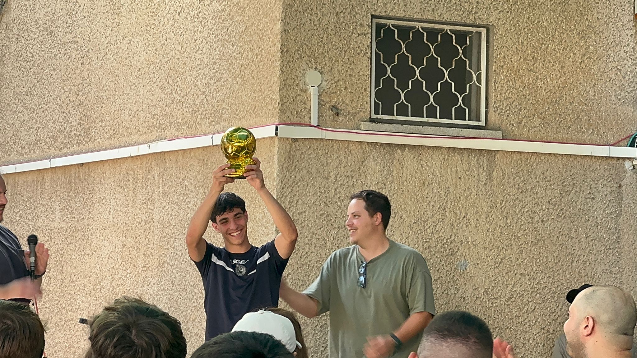 Young man lifting football trophy at tournament